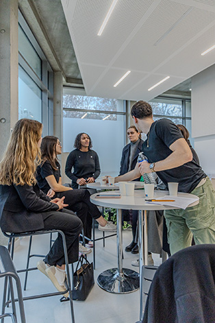 Groupe de femme qui discute autour d'une table avec un homme qui leur sert des verres d'eau